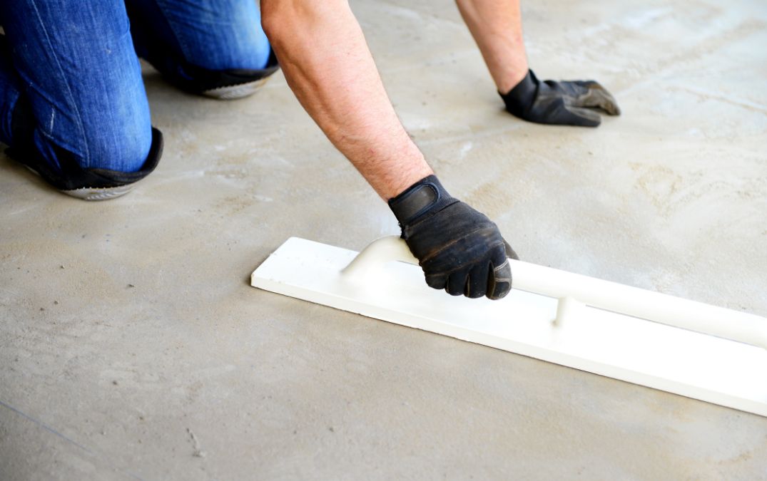 A man leveling out an uneven concrete floor.